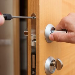 Man fixing the door handle with screwdriver